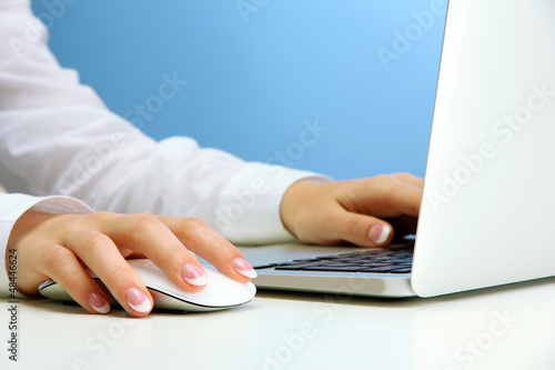 Photo: female hands writing on laptot, on blue background female hands writing on laptot, on blue background