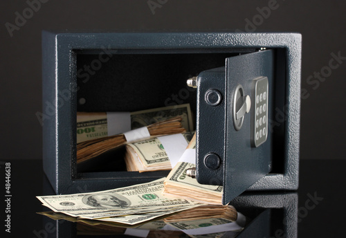 Photo: Money in open safe isolated on black Money in open safe isolated on black
