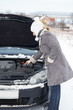 Photo: Car break - woman looks into the engine compartment Car break - woman looks into the engine compartment