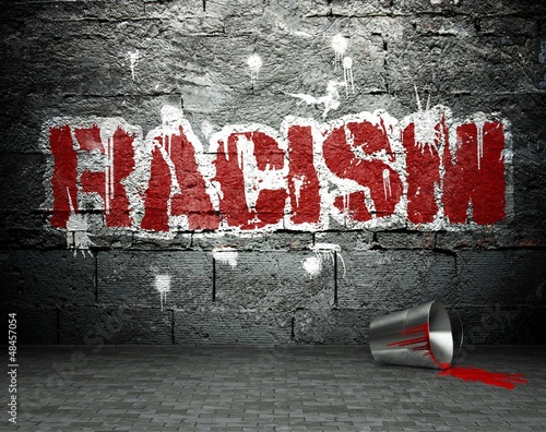 Photo: Graffiti wall with racism, street background Graffiti wall with racism, street background