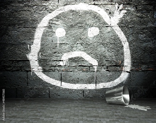 Photo: Graffiti wall with sad face, street background Graffiti wall with sad face, street background