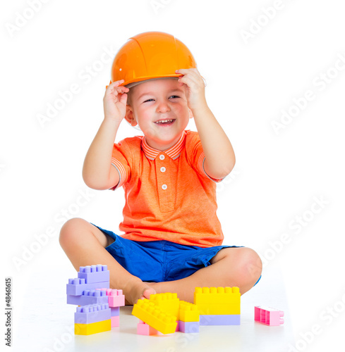 Photo: cheerful child boy with hard hat playing with building blocks to cheerful child boy with hard hat playing with building blocks to