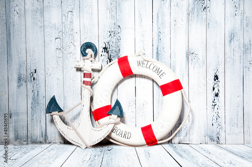 Photo: Anchor and life buoy on a background of white wall. Anchor and life buoy on a background of white wall.