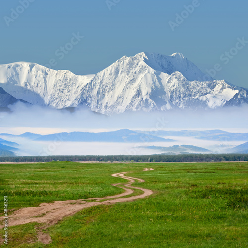 Photo: road among a fields to a mountains road among a fields to a mountains