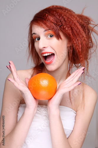Photo: funny redhaired woman with orange in her hands funny redhaired woman with orange in her hands