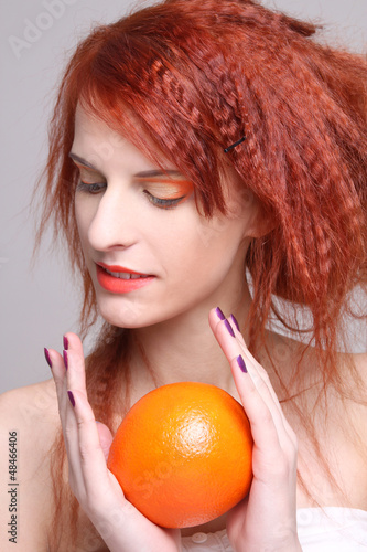 Photo: redhaired girl with orange in her hands redhaired girl with orange in her hands