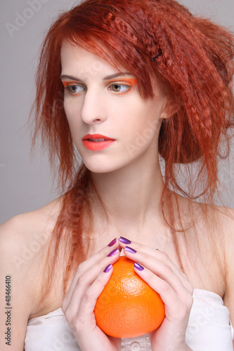 Photo: curly redhaired girl with orange in her hands curly redhaired girl with orange in her hands