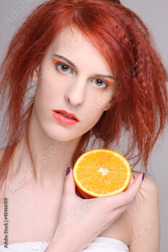 Photo: redhaired woman with orange half in her hand redhaired woman with orange half in her hand