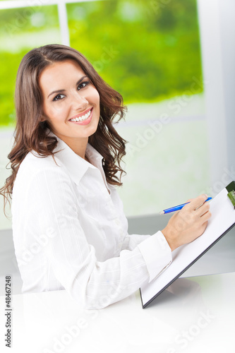 Photo: Young smiling businesswoman working at office Young smiling businesswoman working at office