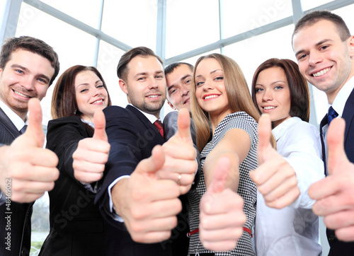Photo: Successful young business people showing thumbs up sign Successful young business people showing thumbs up sign