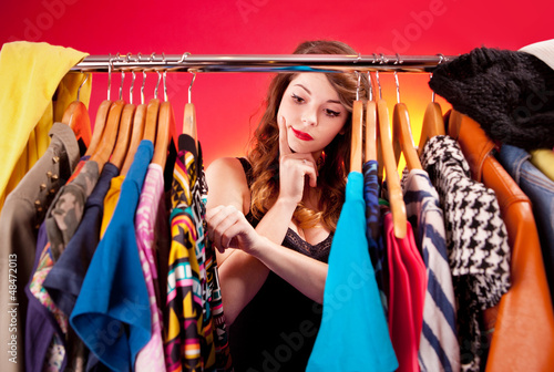 Photo: Nothing to wear concept, young woman deciding what to put on Nothing to wear concept, young woman deciding what to put on