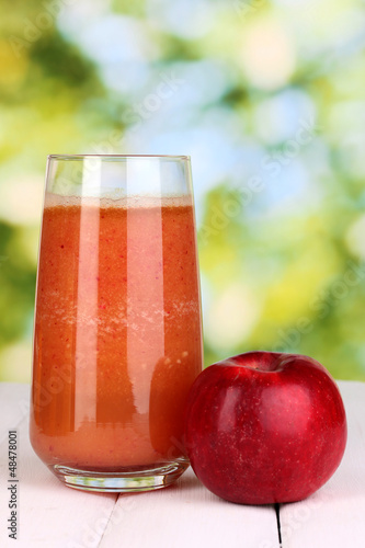 Photo: Glass of fresh apple juice on wooden table, on green background Glass of fresh apple juice on wooden table, on green background