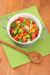Vegetable stew in gray pot on color napkin on wooden background