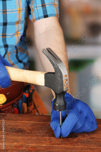Photo: Builder's hands hammering nail into wood Builder's hands hammering nail into wood