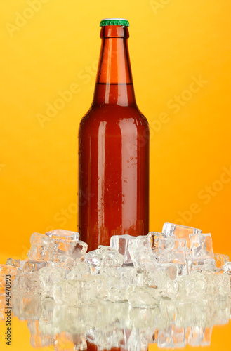 Photo: Beer bottle in ice on orange background Beer bottle in ice on orange background