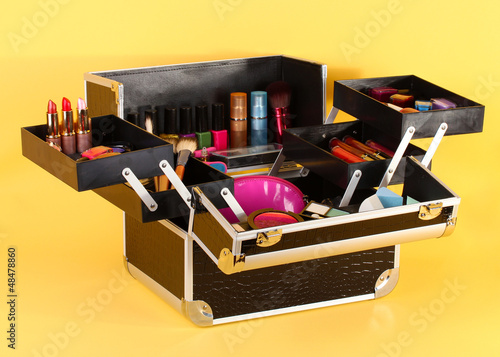 Photo: open case with cosmetics on yellow background open case with cosmetics on yellow background