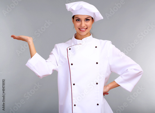 Photo: Portrait of young woman chef on grey background Portrait of young woman chef on grey background
