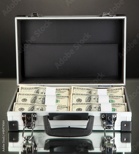 Photo: Suitcase with 100 dollar bills on black background Suitcase with 100 dollar bills on black background