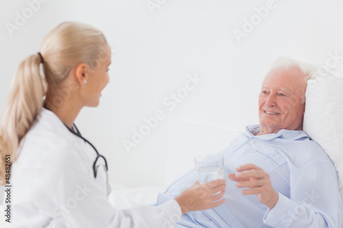 Photo: Doctor handing glass of water to patient Doctor handing glass of water to patient