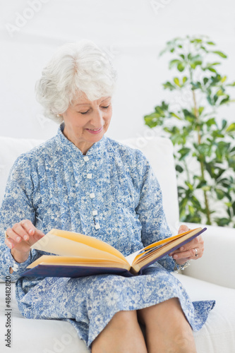 Photo: Elderly happy woman looking at her family album Elderly happy woman looking at her family album