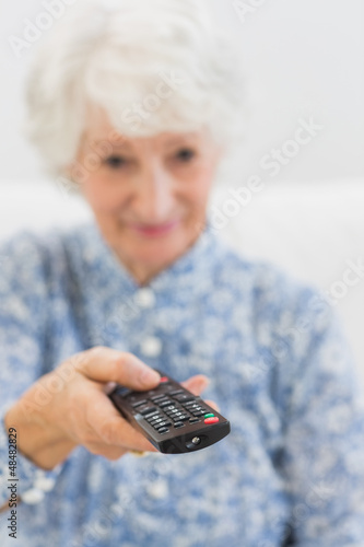 Photo: Elderly cheerful woman using the remote Elderly cheerful woman using the remote