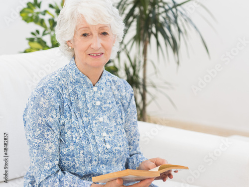 Photo: Elderly cheerful woman reading a old novel Elderly cheerful woman reading a old novel