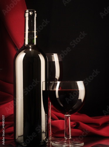 Photo: Red wine glass and bottle on a silk background Red wine glass and bottle on a silk background