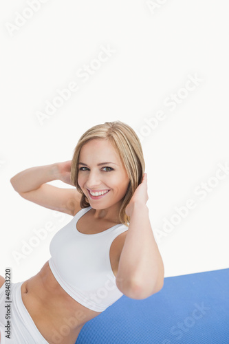 Photo: Portrait of happy woman doing sit-ups on exercise mat Portrait of happy woman doing sit-ups on exercise mat
