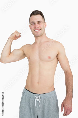 Photo: Portrait of shirtless young man flexing muscles Portrait of shirtless young man flexing muscles