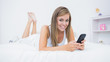 Photo: Happy woman lying on the bed with her phone Happy woman lying on the bed with her phone