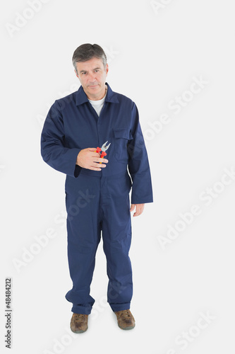 Photo: Mature technician holding pliers Mature technician holding pliers
