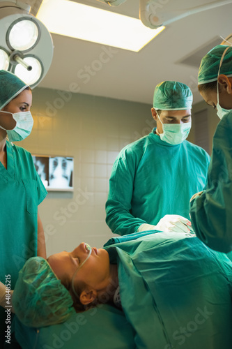 Photo: Team of surgeons working on a female patient Team of surgeons working on a female patient