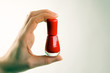 Hand hält rotes Nagellackfläschchen