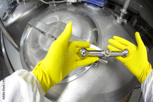 Photo: hands in yellow gloves closing industrial process tank hands in yellow gloves closing industrial process tank
