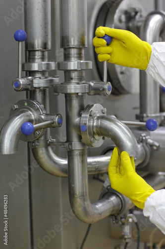 Photo: hands in yellow gloves on tap and lever of technological system hands in yellow gloves on tap and lever of technological system