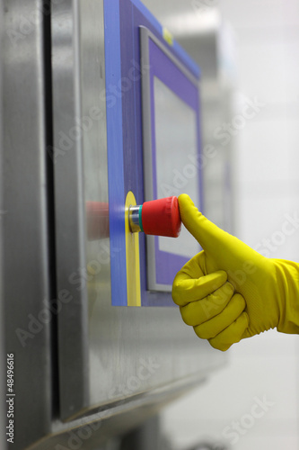 Photo: hand in glove pressing button at control panel in plant hand in glove pressing button at control panel in plant