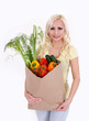 blonde young woman with vegetables in shopping bag on white