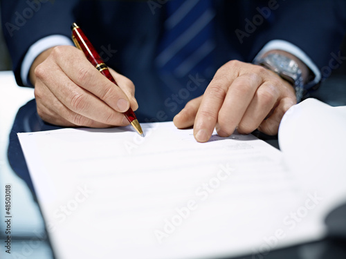 Photo: Close up of businessman signing a contract. Close up of businessman signing a contract.