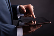 Closeup of businessman holding digital tablet on black backgroun