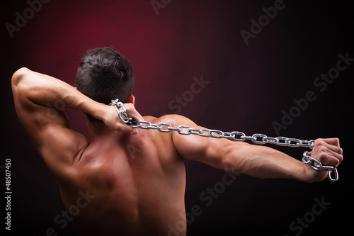 Photo: Muscular young man from back on black background Muscular young man from back on black background