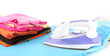 Flat electric iron and clothes isolated on white