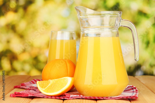 Photo: Full glass and jug of orange juice and oranges Full glass and jug of orange juice and oranges