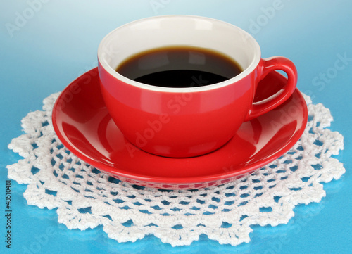 Photo: A red cup of strong coffee on blue background A red cup of strong coffee on blue background