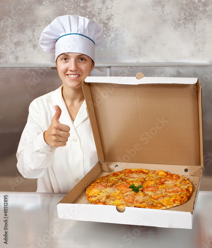 Photo: female cook with pizza at kitchen female cook with pizza at kitchen