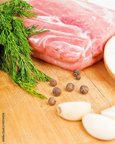 Photo: Raw fresh meat on board with condiments on white background Raw fresh meat on board with condiments on white background