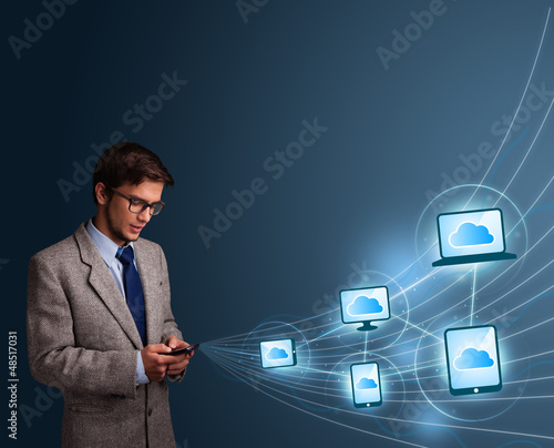 Photo: Handsome man typing on smartphone with cloud computing Handsome man typing on smartphone with cloud computing