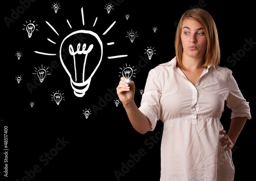 Photo: Woman drawing light bulb on whiteboard Woman drawing light bulb on whiteboard