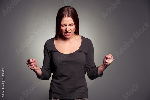 Photo: angry young woman over dark background angry young woman over dark background