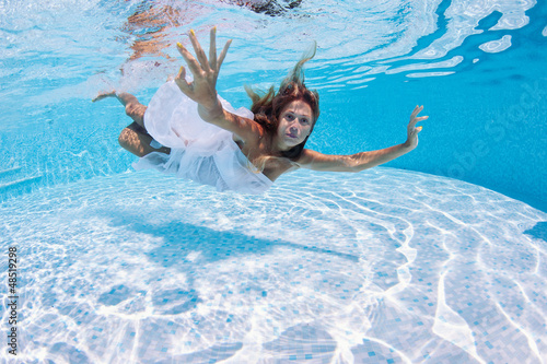 Photo: Underwater girl portrait with white dress in swimming pool. Underwater girl portrait with white dress in swimming pool.