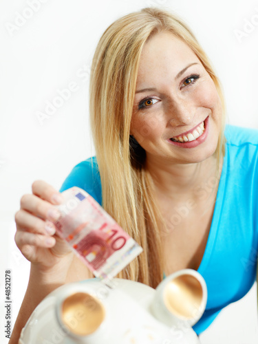 Photo: Woman is happy to save money in her piggy bank Woman is happy to save money in her piggy bank